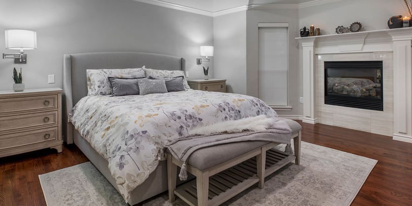Arlington bedroom remodel with fireplace, soft gray walls, and wood floors by Medford Design-Build