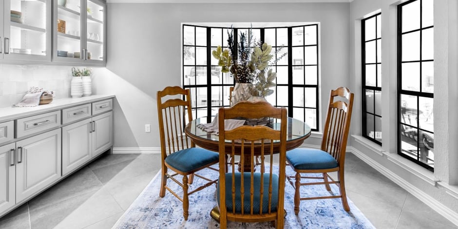 Dining area remodel with large black-framed windows and glass-front cabinets by Medford Design-Build