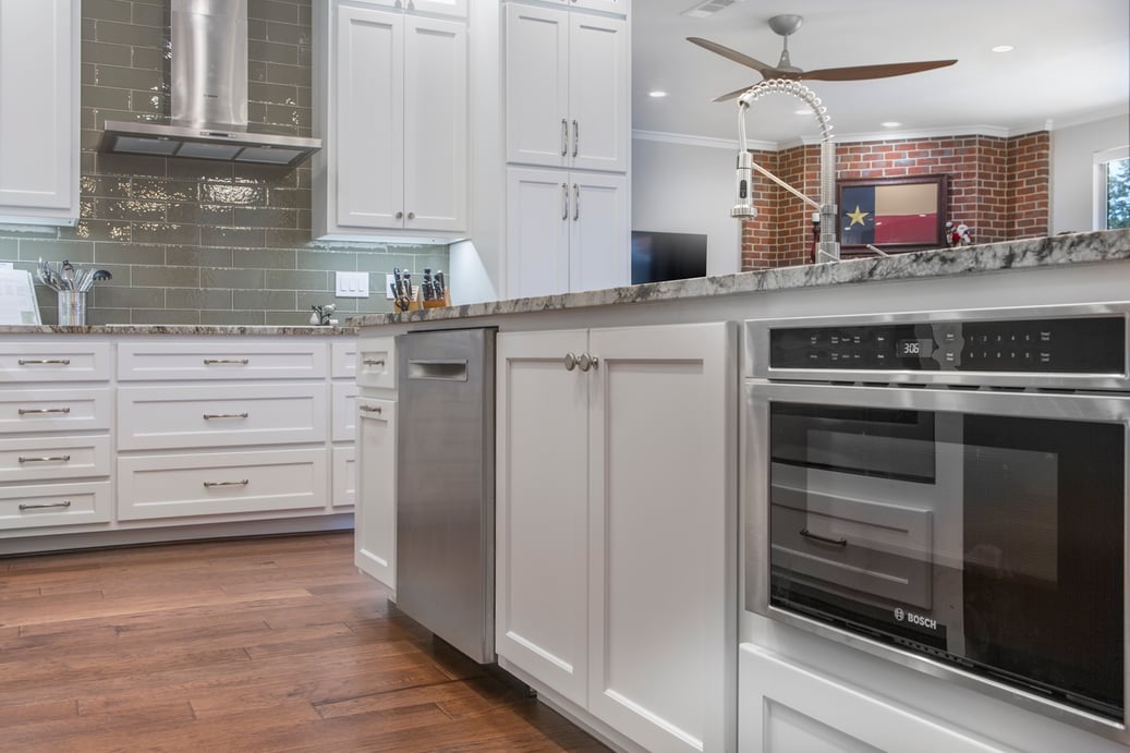 angled shot of kitchen island showcasing under counter microwave drawer, dishwasher, and pull-out trash bin.